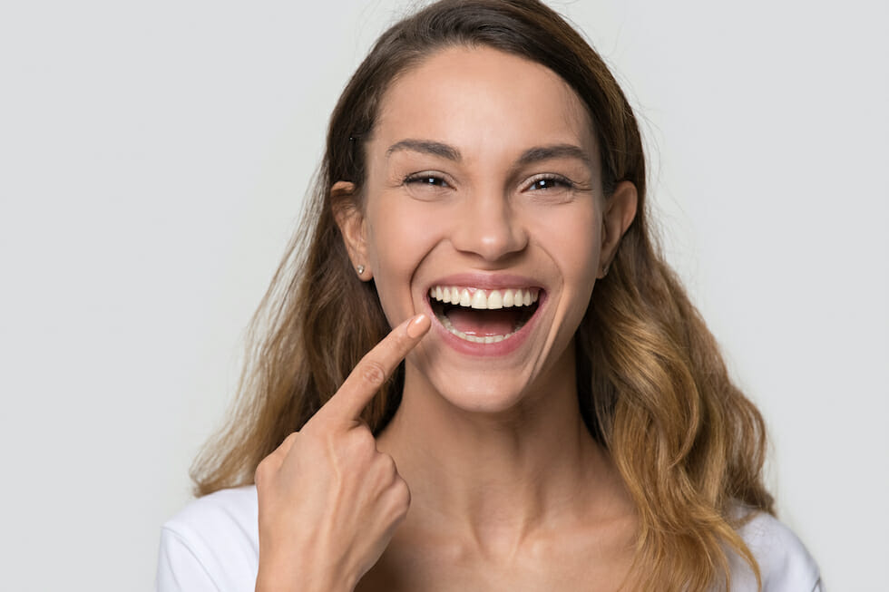 woman smiling big pointing at mouth